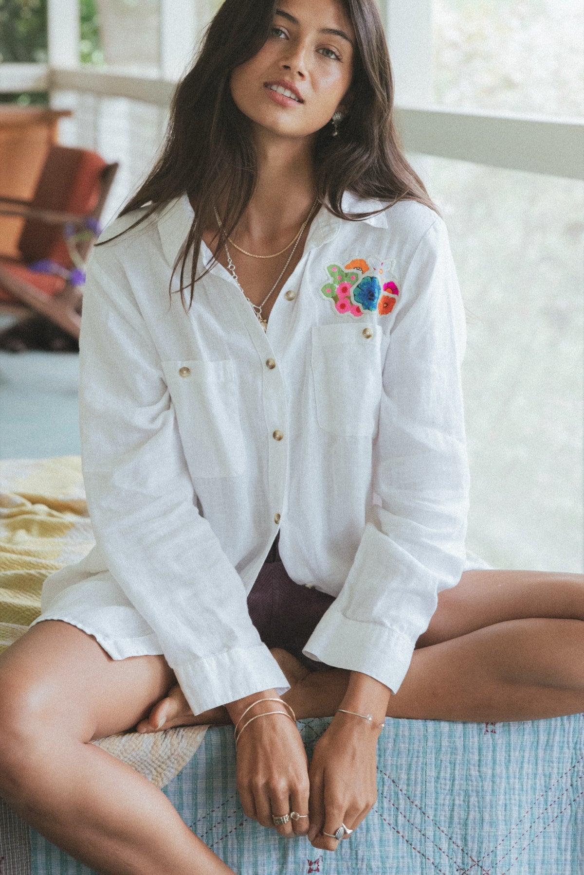 Model in a white sun and moon shirt sitting on a bed