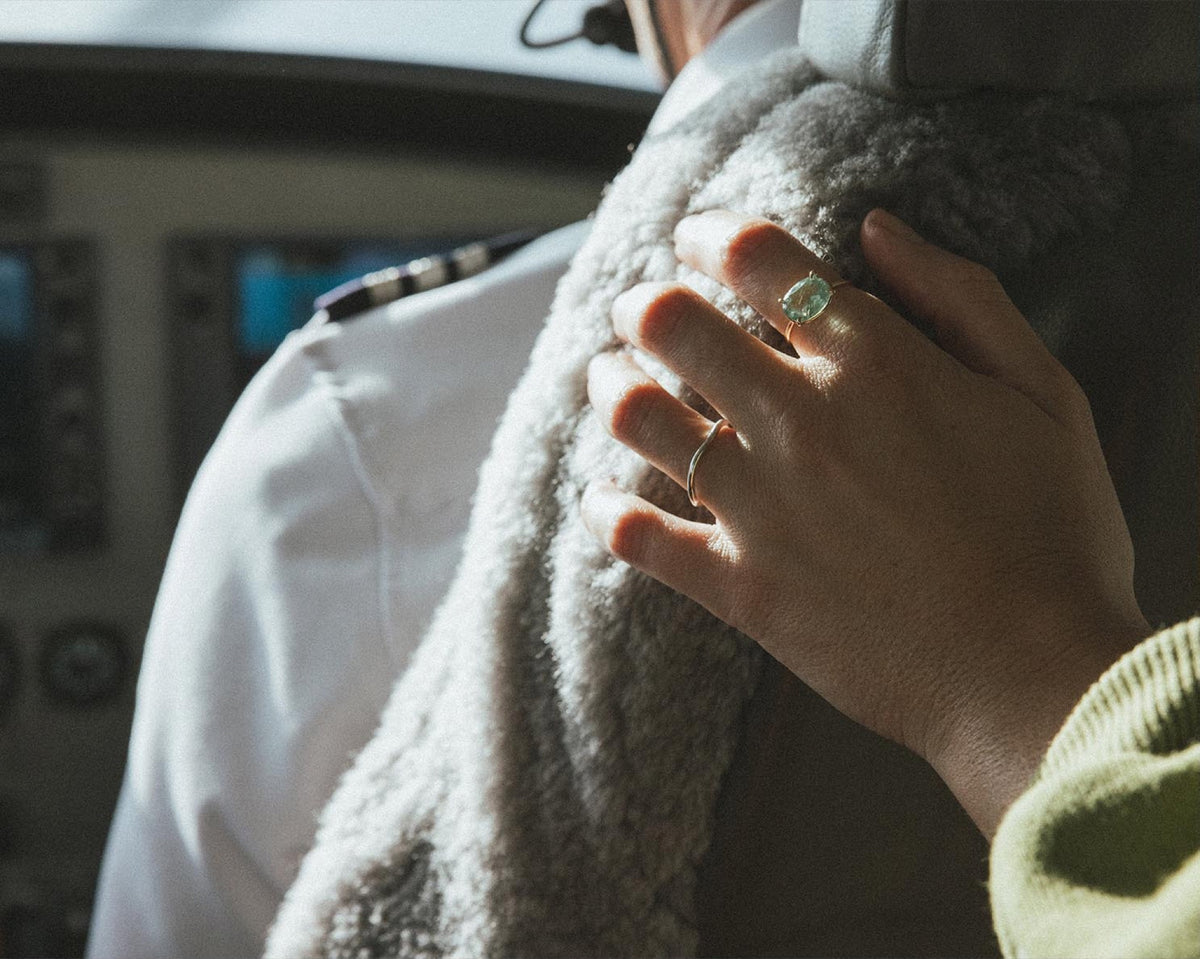 Hand with rings on a grey sweater in a plane