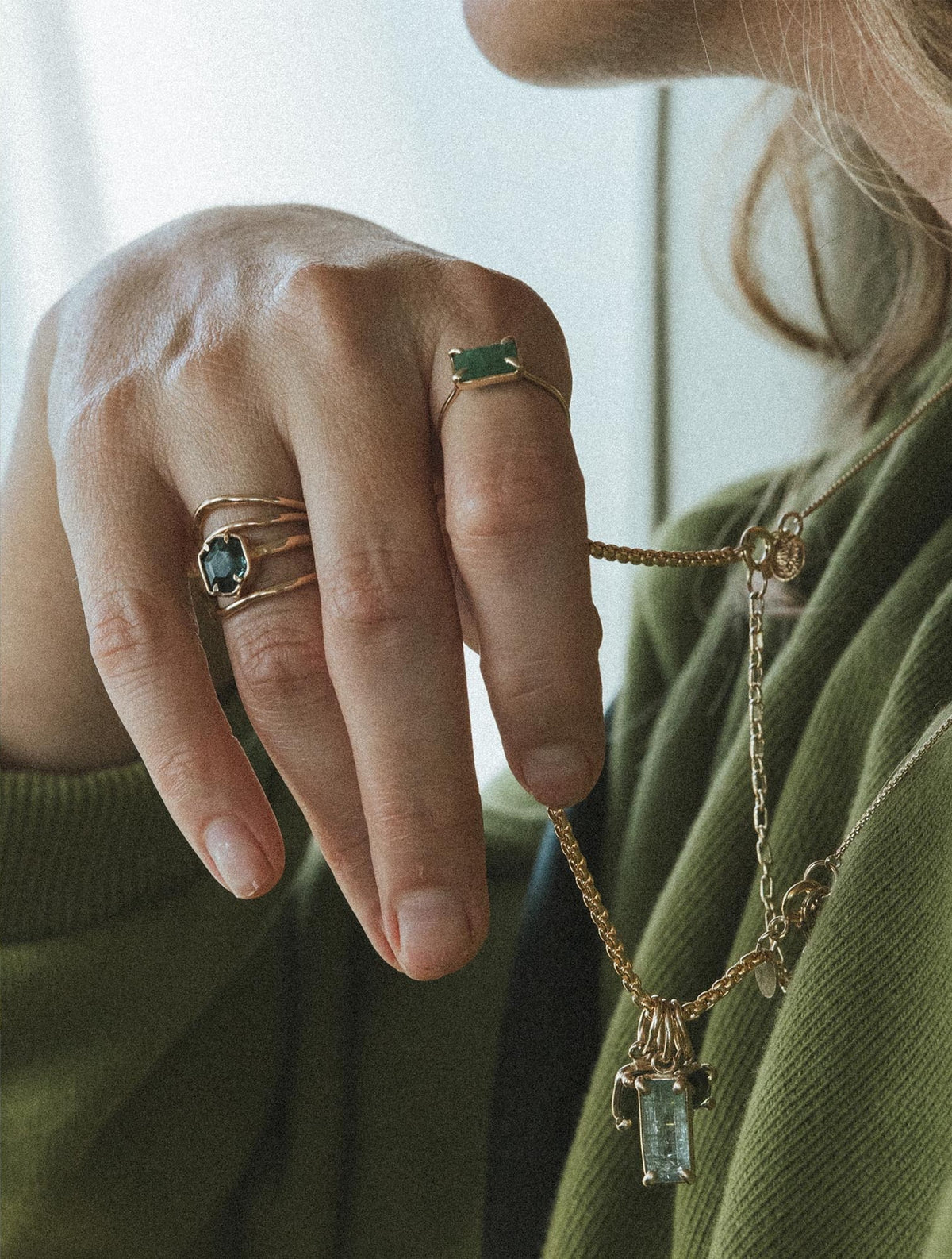 Hand with rings against a green sweatshirt