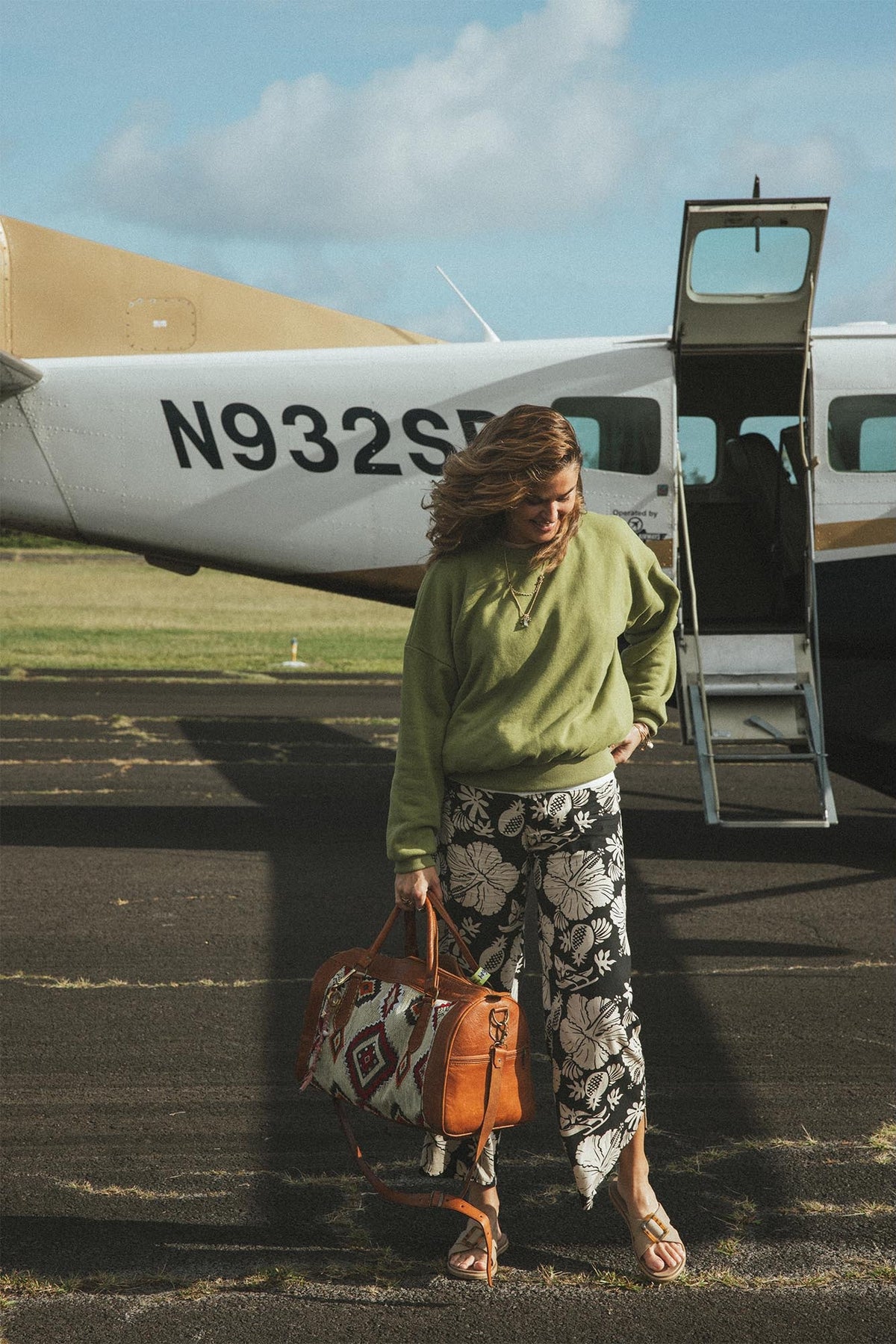 Model in a green sweatshirt by a plane