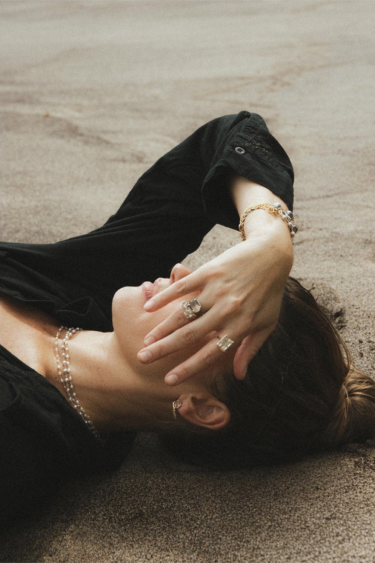 Model resting her face on her arm on the sand