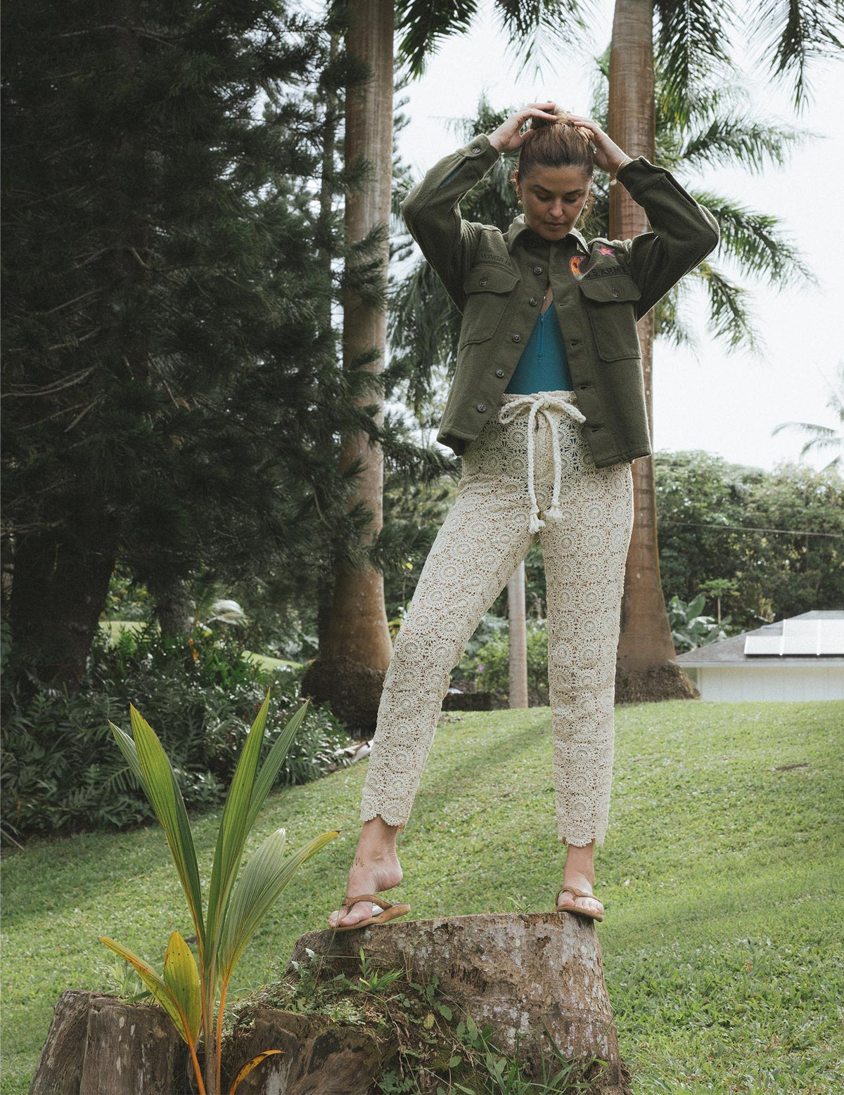 Model in an olive jacket among palms