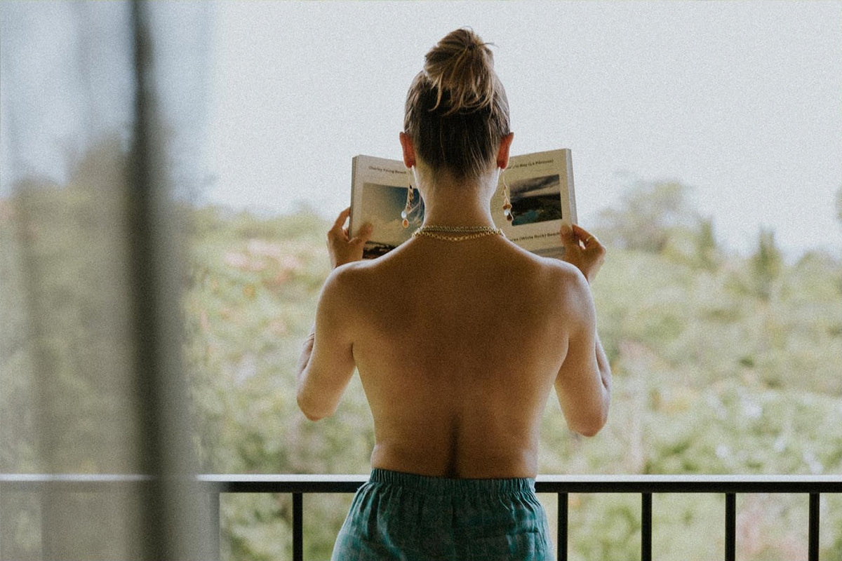 Model seen from behind reading on a balcony