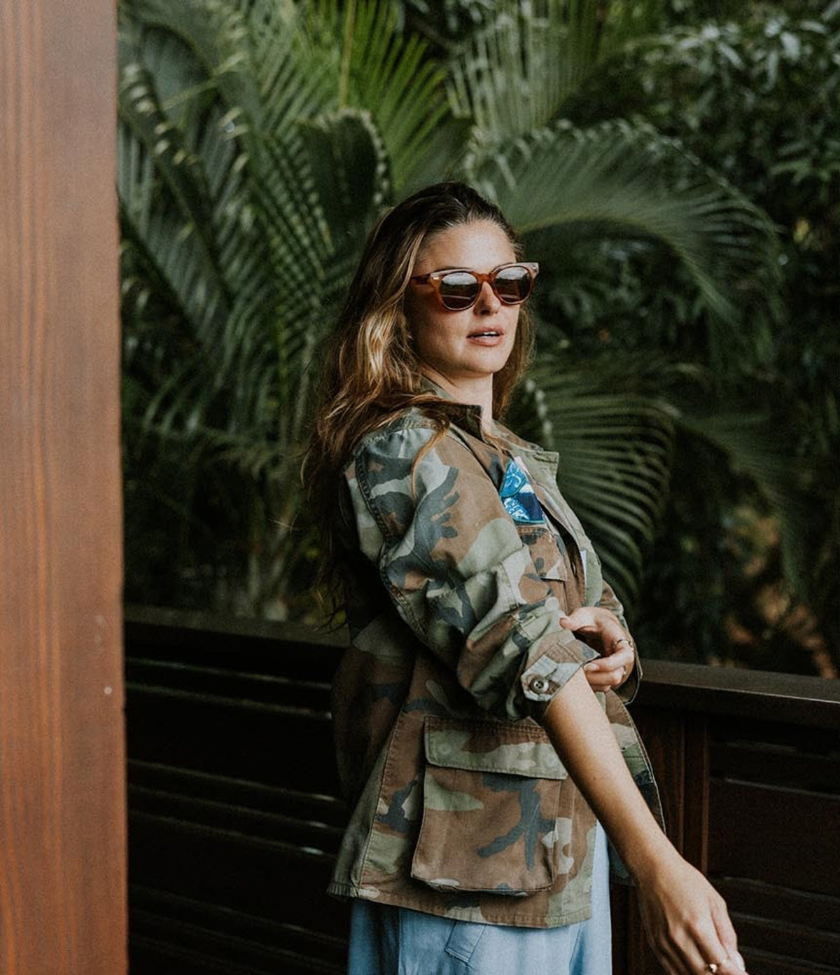 Model in a camo jacket among palms