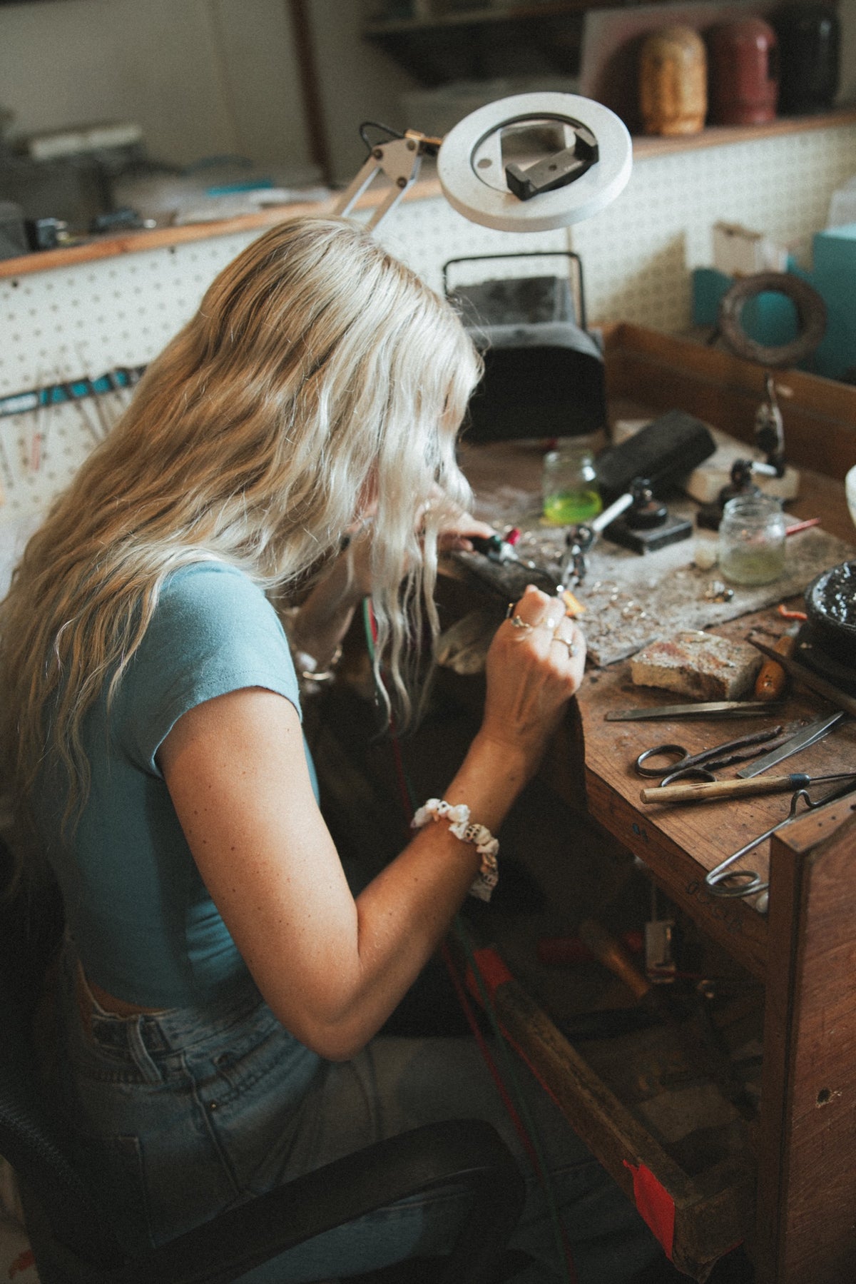 Jeweller working at the studio bench under a magnifying lamp