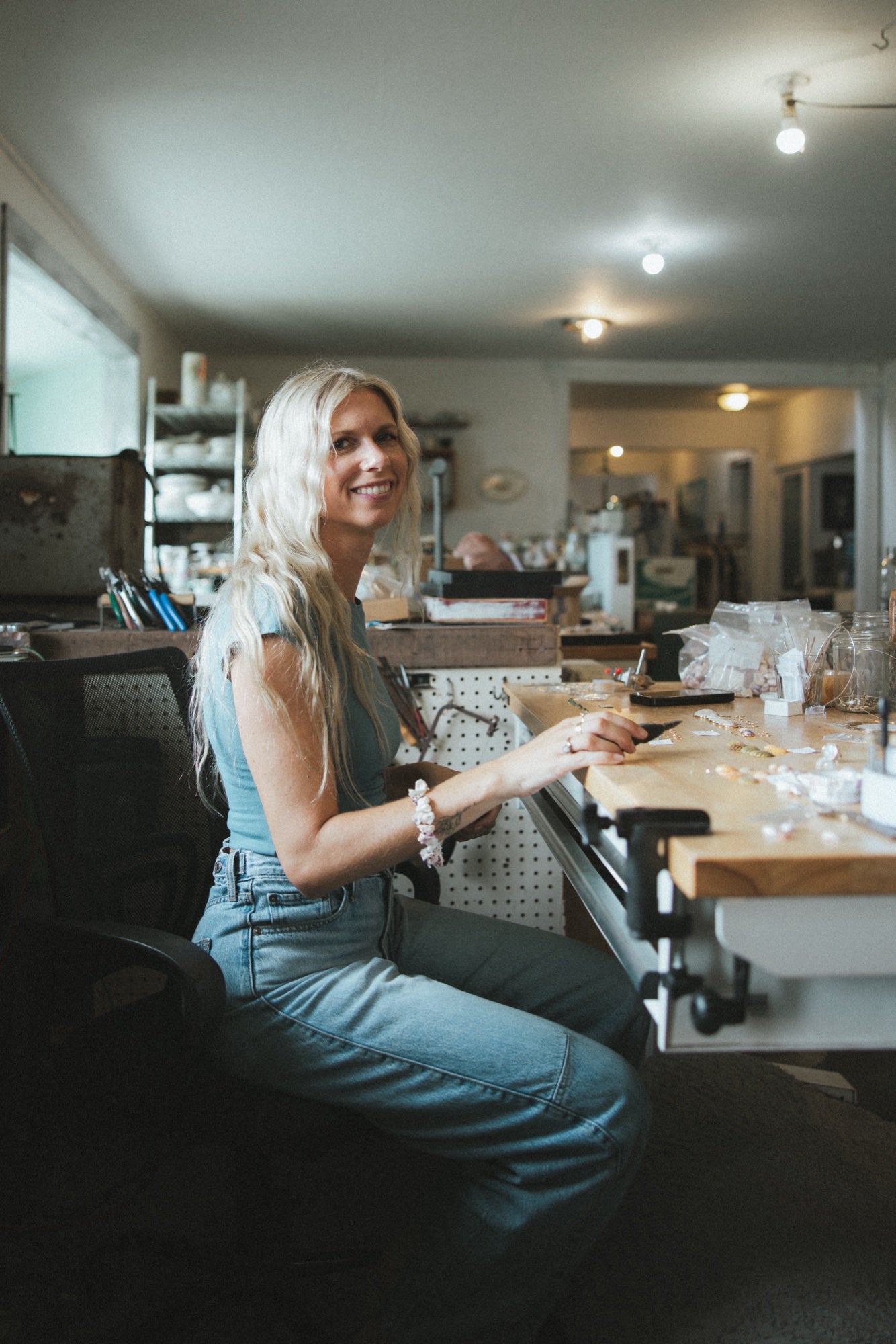 Jeweller smiling at her bench in the Wings studio