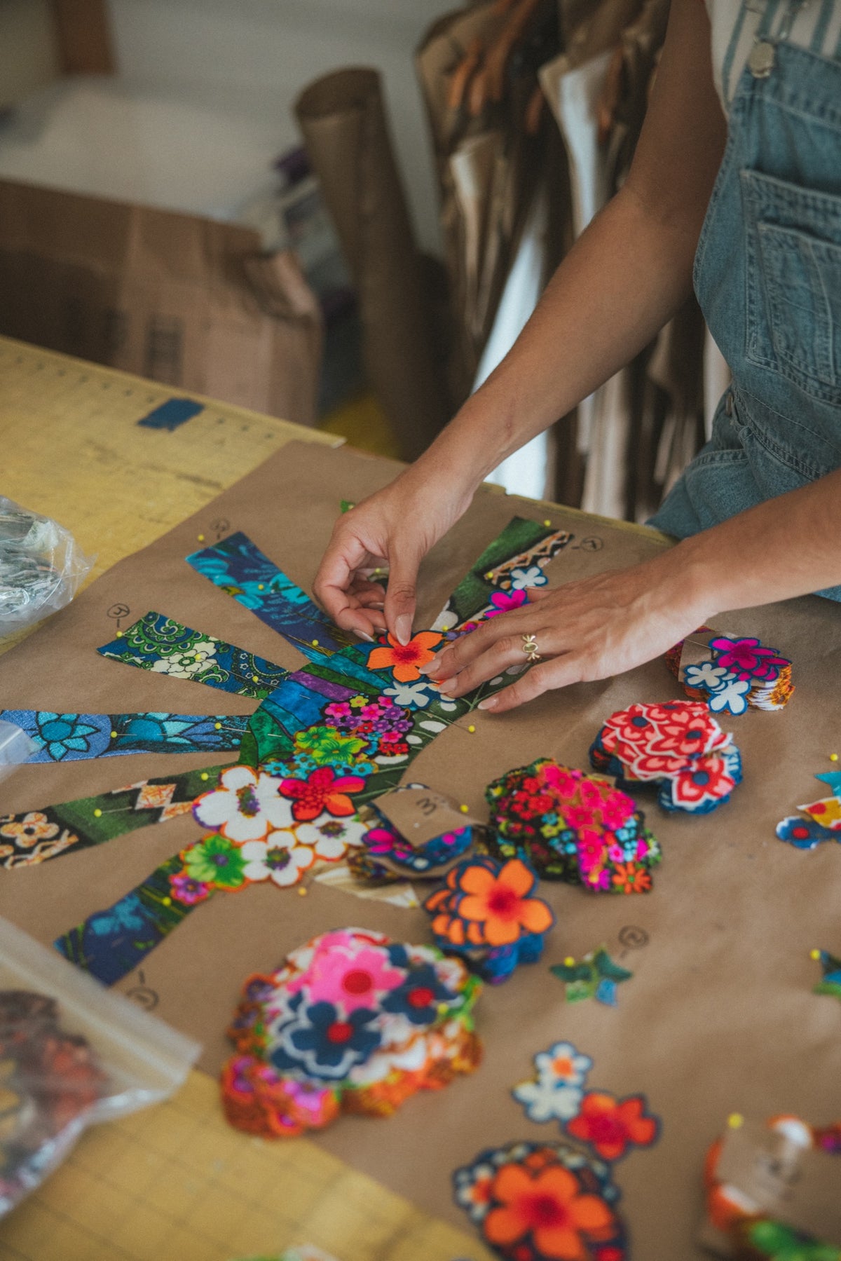 Hands arranging embroidered flower patches on the cutting table