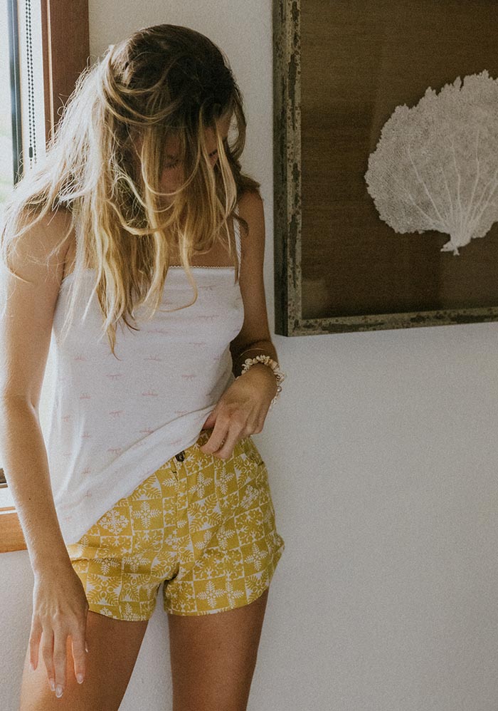 Model in yellow shorts and a white tank